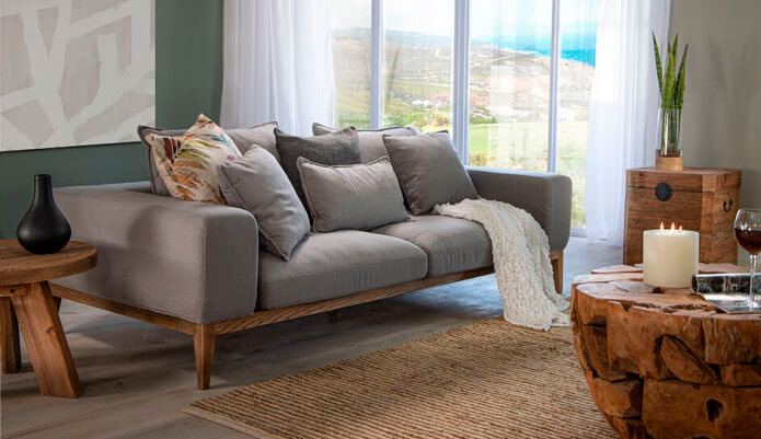 Comfy grey couch with lots of scatter cushions in living room with wooden coffee table and side tables